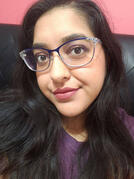 A selfie of Leona in blue glasses and a pink shirt smiling at the camera.